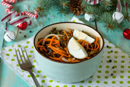 Homemade appetizer on a festive Christmas table. Salad with egg, Korean carrots and sea kale.の写真素材