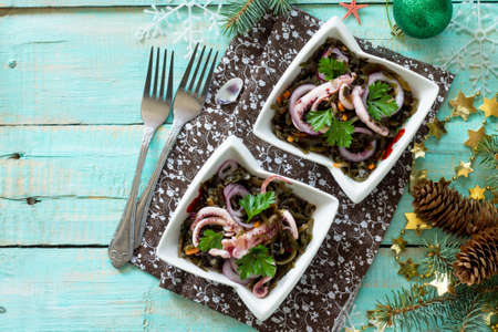 Homemade appetizer on a festive Christmas table. Salad with octopus and sea cabbage.の写真素材