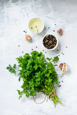 Fresh parsley and various spices on a light stone or slate background.の写真素材