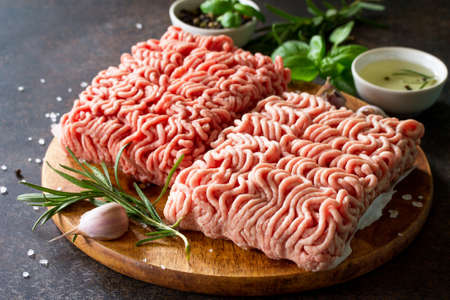Assorted minced pork and beef with fresh leaves of rosemary and basil.の写真素材