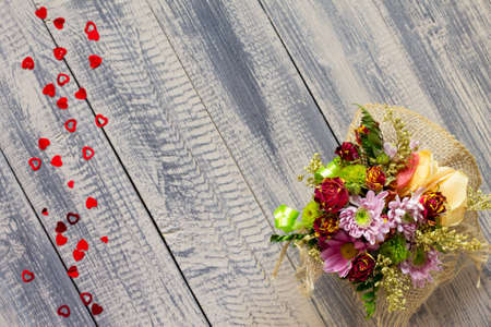 Background Valentine's Day or wedding. Basket bouquet of roses and chrysanthemums on a vintage wooden background. Flat lay. Top view with copy space.
の写真素材