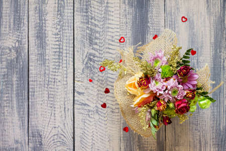 Background Valentine's Day or wedding. Basket bouquet of roses and chrysanthemums on a vintage wooden background. Flat lay. Top view with copy space.の写真素材