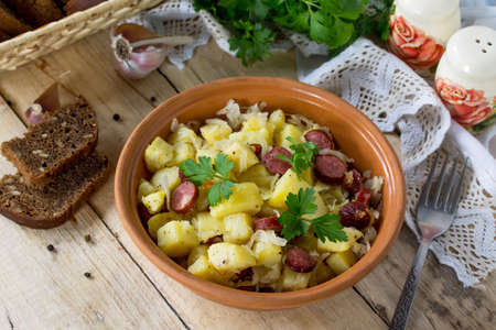 Homemade snacks on the kitchen wooden table in a rustic style. Warm salad with potatoes and smoked sausages.の写真素材