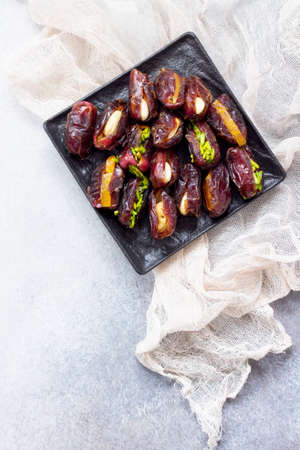 Stuffed dates with nuts and candied fruit filling on a stone or slate background. The concept of a healthy dessert. Flat lay. Top view.の写真素材