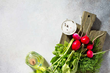 Radish. Red fresh radish, olive oil and fresh herbs on a stone or slate background. Flat lay. Top...