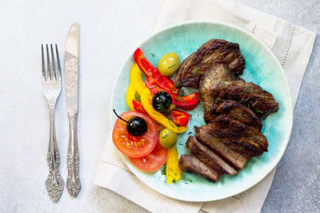 Appetizing barbecue steak from beef tenderloin and fresh vegetables salad on concrete, stone or slate background. Top view.の写真素材