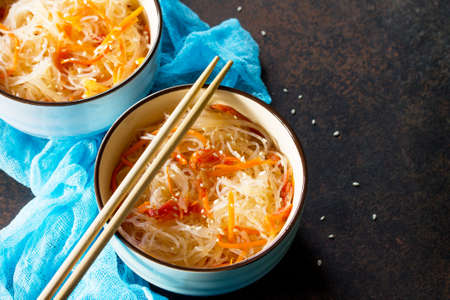 Funchoza salad with rice noodles with paprika, tomatoes and pepper on a dark stone or slate...