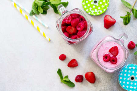 Fresh berry smoothies and fresh strawberries and raspberries on a gray stone or slate background. The concept of proper nutrition and health or detoxification. Copy space.の写真素材