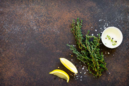 Ingredients for cooking on a dark stone table - thyme, olive oil and lemon. Copy space, top view flat lay background.の写真素材