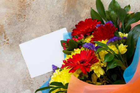 Mother's Day background or greeting card. Congratulatory sheet of paper withbouquet of gerbera and chrysanthemums on a stone background or slate with copy space.の写真素材