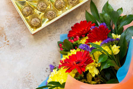 A wedding story or background Mother's Day. Basket bouquet of gerbera with chrysanthemums and sweets on a stone background or slate with copy space. の写真素材