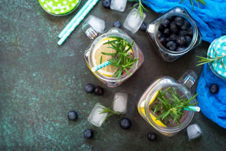 Mason jar mugs with homemade refreshing drink with blueberries and rosemary. The concept of proper nutrition and health or detoxification. Copy space, top view of a flat background.の写真素材