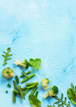 Food background. Various summer green vegetables, spices and fresh herbs on blue concrete background. Copy space, top view flat lay background.の写真素材