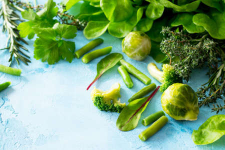 Food background. Various summer green vegetables, spices and fresh herbs on blue concrete...