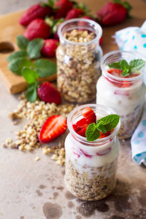 Homemade healthy breakfast with homemade baked granola, fresh strawberry and yogurt on stone or concrete table. Copy space.の写真素材