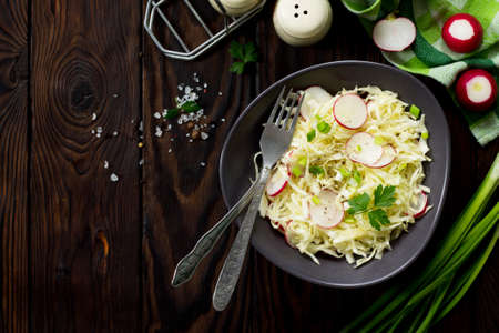 Diet, concept of vegetarian food. Summer salad with fresh cabbage and radish dressed with olive oil on a wooden table. Healthy proper nutrition. Top view flat lay background.
の写真素材