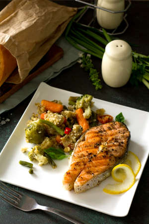 Grilled salmon steak, couscous and vegetables (string beans, brussels sprouts, carrots, sweet peppers, tomatoes) on stone or concrete table. Healthy proper nutrition.の写真素材