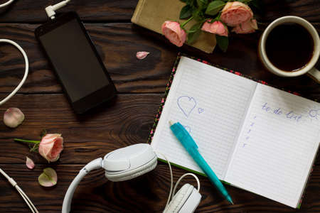 To do list conceptual. Smartphone, headphones, coffee cup and notebook on a wooden table. Top view flat lay background.の写真素材
