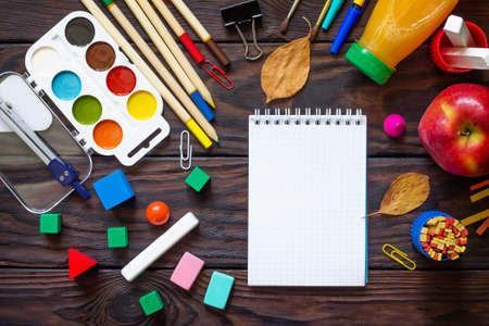 Back to school background with school supplies, autumn leaves and apple on a wooden table. Top view flat lay background, copy space.の写真素材