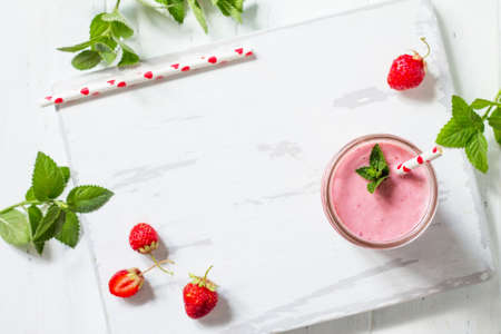 Strawberry milkshake or smoothie on a white wooden background. Healthy juicy vitamin drink diet or vegan food concept. Top view flat lay background.の写真素材