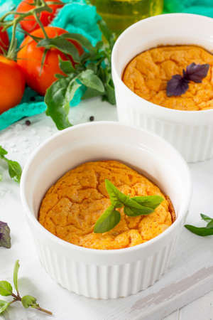 Vegetarian vitamin breakfast French baked cheese souffle with tomato close-up on a wooden table....