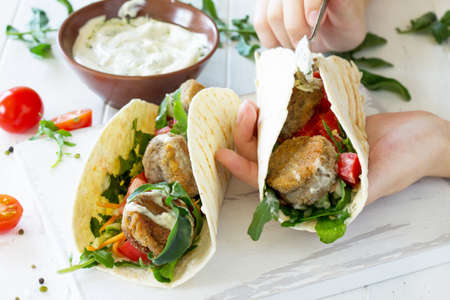 Arabic cuisine. Concept of vegetarian food. Delicious fresh homemade vegetarian tortilla with falafel on a wooden kitchen table. Cooking.の写真素材