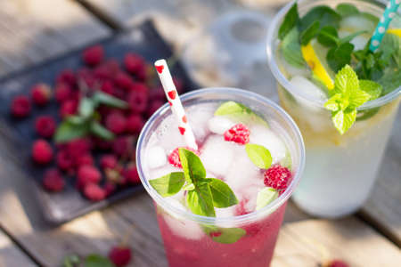 SOFT DRINKS. Refreshing summer drink lemon with mint, ice and raspberry with basil, ice. Glasses...