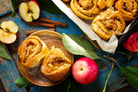 Fresh Homemade Rolls Buns with apples and cinnamon in glaze on a blue vintage wooden background. Top view flat lay background.の写真素材