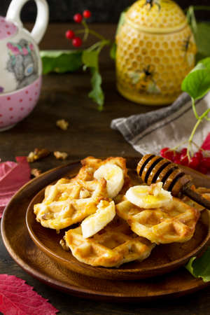Thanksgiving baking. Belgian Walnut Wafers on a wooden kitchen table, served with fresh banana slices and honey.の写真素材