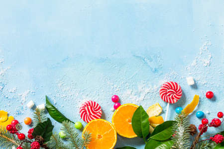 Fresh and juicy tangerines, a variety of Christmas sweets and Christmas branches spruce on blue a...
