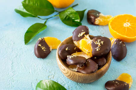Slices of Tangerines in Chocolate. Dessert Tangerines on a blue stone or concrete background. Copy...