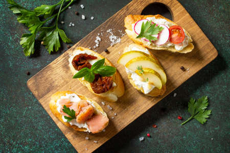Italian Antipasti snacks set for Wine. Variety Brushetta with Soft Cheese, Pear, Radish, Salmon and...