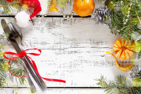 Christmas tree branch, ornaments and cutlery on a white wooden table.の写真素材