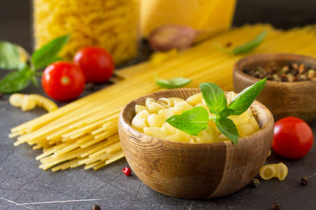 Various Pasta, Cheese, Spice and Tomatoes. Ingredients for cooking Pasta on a stone table.の写真素材