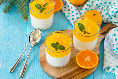 Italian dessert, homemade cuisine. Panna cotta with tangerines jelly and minton a wooden table. Copy space.の写真素材