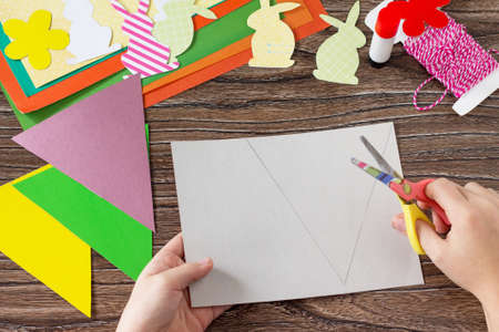 The child cuts out details festive Easter garland on a wooden background. Project of children's creativity, handicrafts, crafts for kids.
の写真素材