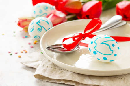 Easter table setting with tulips flowers, Easter eggs and cutlery. Holidays background. Copy space.