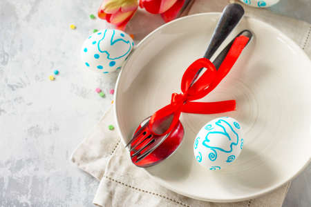 Easter table setting with tulips flowers, Easter eggs and cutlery. Holidays background. Copy space.