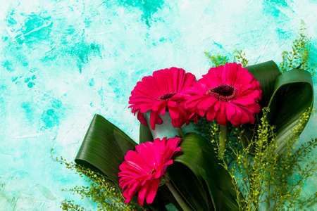Mother's Day background or greeting card. Bouquet Red Flowers of gerbera on a turquoise stone table....