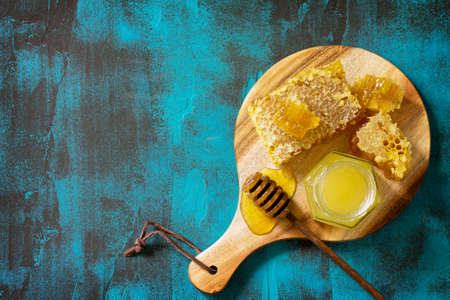 Natural Honey. Honey in glass jar and dipper, Sweet Honeycombs on blue stone table. Top view flat...