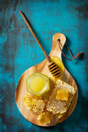 Natural Honey. Honey in glass jar and dipper, Sweet Honeycombs on blue stone table. Top view flat...