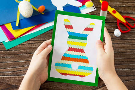 A child is holding an Easter postcard Easter bunny. Handmade. Project of children's creativity,...