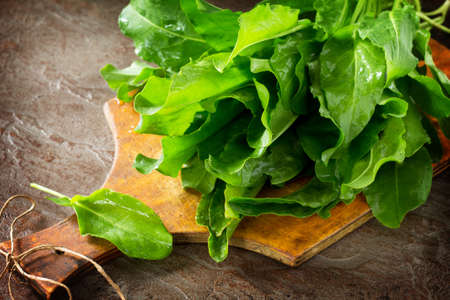 Fresh spinach leaves over dark slate, stone or concrete background.