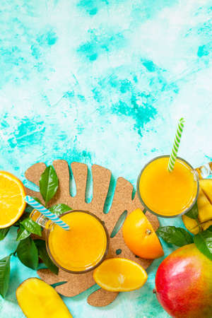Concept of vegetarian food, fresh vitamins. Refreshing summer mango and citrus freshly squeezed juice on stone table. Top view flat lay background with copy space.の写真素材