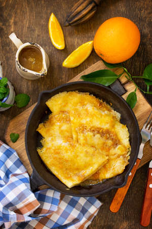 Homemade French pancakes - Crepe Suzette with orange syrup for a delicious breakfast. Top view flat lay background.の写真素材