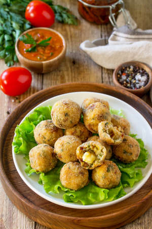Arancini. Italian Rice Balls with Mozzarella and Sun-dried tomatoes, with tomato sauce on wooden...