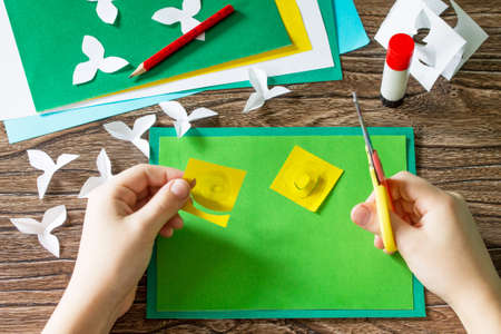 The child cuts details Mother's Day card with daffodils. Handmade. Project of children's creativity, handicrafts, crafts for kids.の写真素材