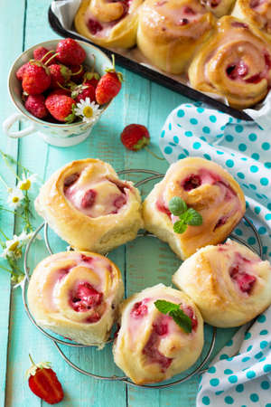 Fresh Homemade Rolls Buns with strawberry with Cream Cheese in glaze for Breakfast on kitchen table.