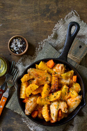 Chicken stew with caramelized pear on rustic wooden table. Free space for your text. Flat lay. Top...