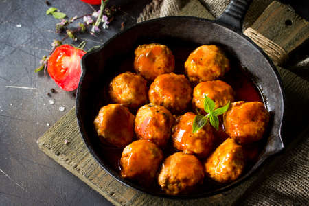 Homemade Meatballs with spices and tomato sauce in a frying pan on dark stone table. Free space for your text.の写真素材